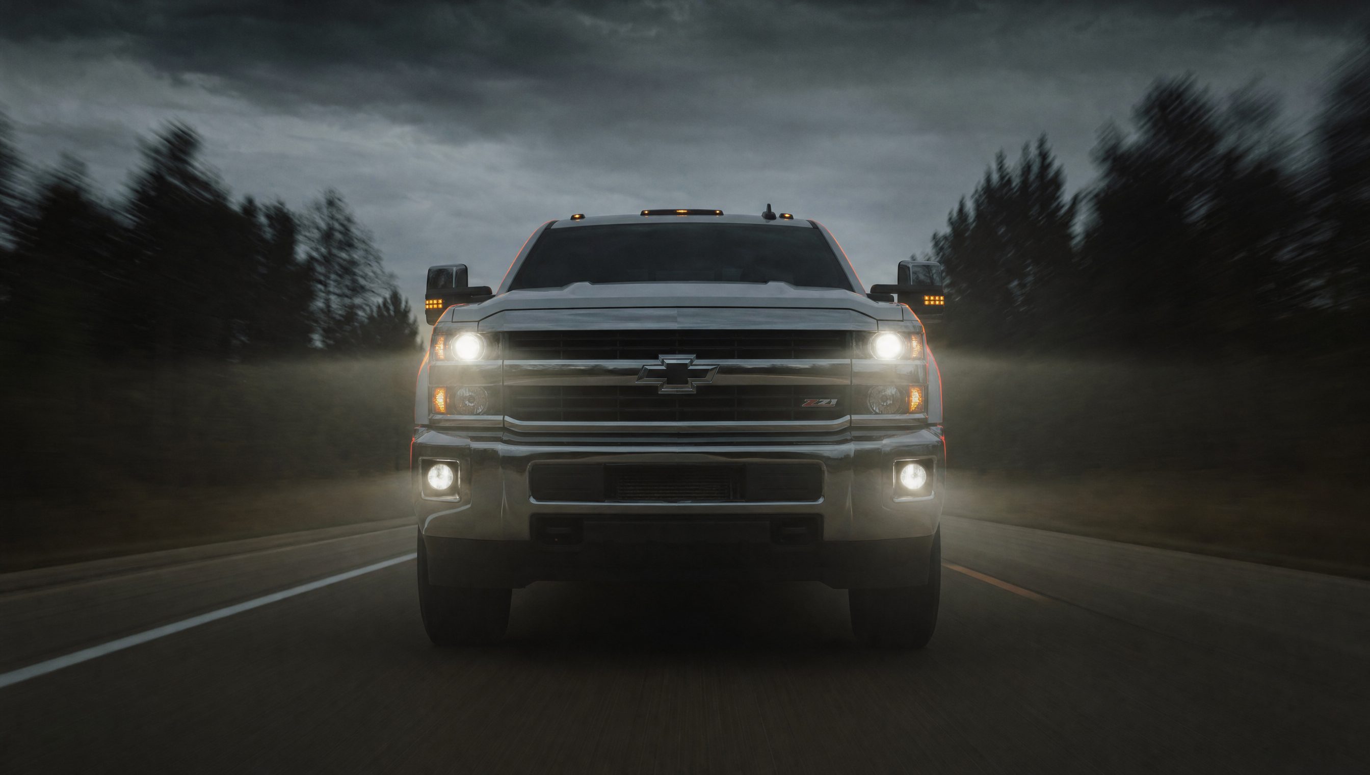 White Chevy Duramax driving at night, headlights on